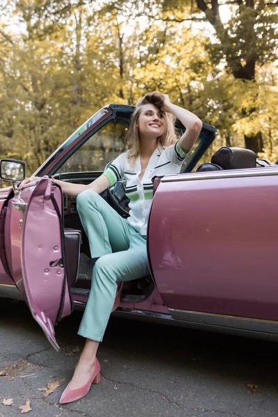 Cheerful Woman Looking Away Touching Hair While Stepping Out Cabriolet — Stock Photo, Image