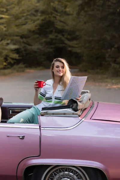 Ευτυχισμένη Γυναίκα Κρατώντας Φλιτζάνι Καφέ Και Χάρτη Ενώ Κάθεται Cabriolet — Φωτογραφία Αρχείου