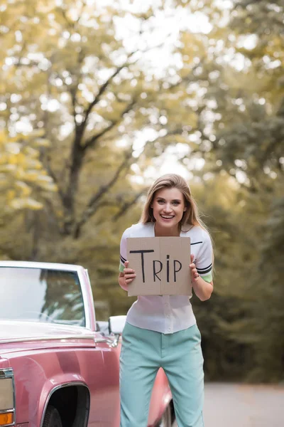 Excited Young Woman Holding Placard Trip Lettering Retro Convertible Car — Stock Photo, Image