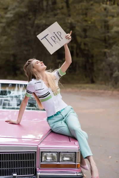 Mujer Sonriente Sosteniendo Pancarta Con Letras Viaje Mientras Está Sentado —  Fotos de Stock