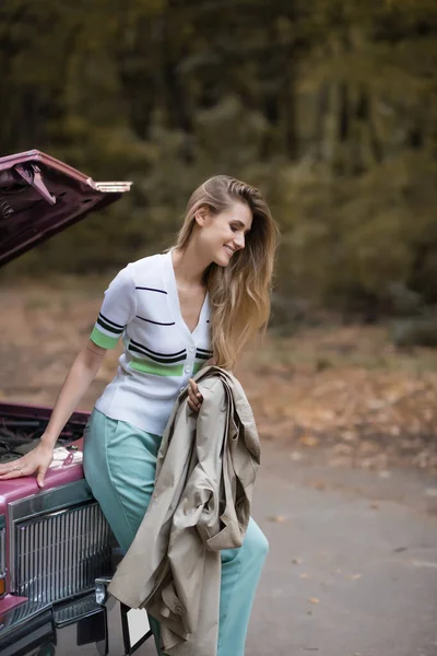 Smiling Woman Holding Cape While Standing Broken Vintage Car Road — Stock Photo, Image