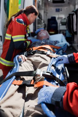 Selective focus of paramedics standing near patient on stretcher and ambulance auto clipart