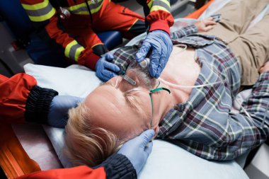 Ambulansta oksijen maskesi takan bir meslektaşın yanında duran sağlık görevlisinin seçici odak noktası. 
