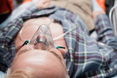 Oksijen maskeli yaşlı adamın seçici odak noktası ambulans arabasında yatıyor. 
