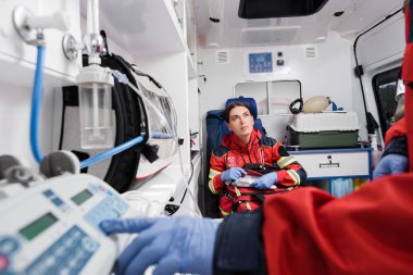 Ambulans arabasında ekipman kullanan ilk yardım çantasını meslektaşının yanında tutan sağlıkçıların seçici odak noktası 