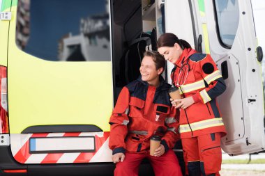 Ambulans arabasının yanına gitmek için üniformalı sağlık görevlileri kahve tutuyor. 