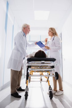 Doktorlar klinikte sedye üzerinde hastanın yanındaki panoya bakıyorlar. 