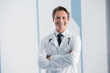 Doctor with crossed arms looking at camera in clinic  clipart