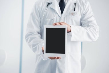 Hastanedeki boş ekranla dijital tableti gösteren doktorların kırpılmış görüntüsü 