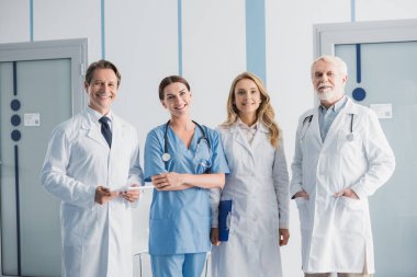Doktorlar ve hemşire klinikteki kameraya pano ve dijital tabletle bakıyor. 