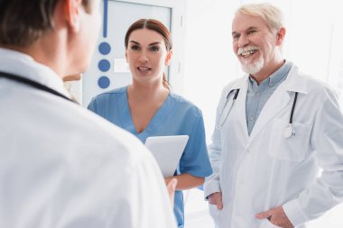 Dijital tabletli hemşirelerin seçici odağı hastanede doktorla konuşuyor.