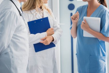 Hemşirenin elinde dijital tabletle doktorların yanında pano tutarken çekilmiş görüntüsü. 