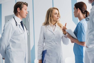 Doktorun seçmeli odak noktası pano ile işaret ederek meslektaşlarının yanında ve dijital tabletli hemşire 
