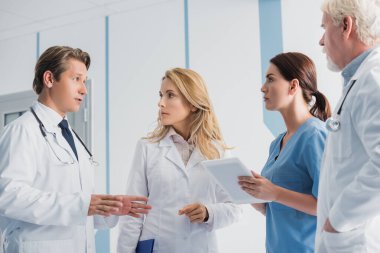 Doktorun, meslektaşlarının yanında ellerini göstermesi ve dijital tabletli hemşirelerin seçici odağı 