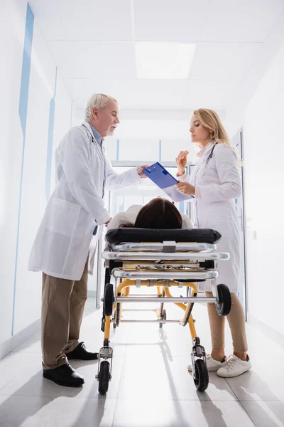 Doctors Looking Clipboard Patient Stretcher Clinic — Stock Photo, Image