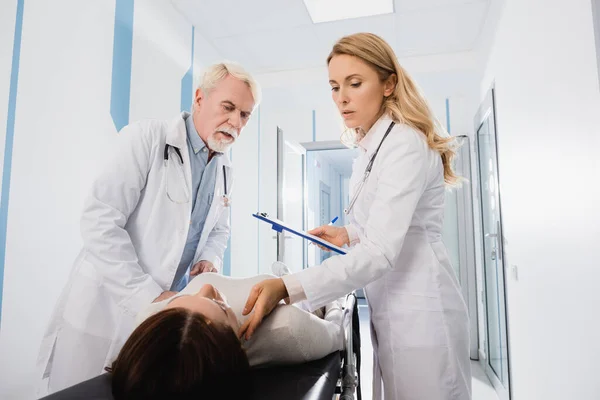 Selective Focus Doctor Clipboard Checking Pulse Patient Stretcher Colleague Clinic — Stock Photo, Image