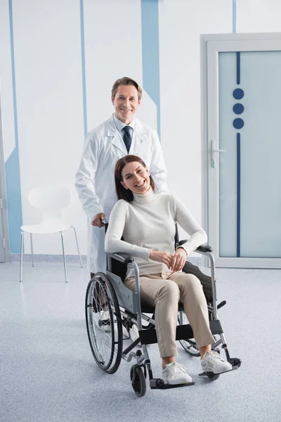 Doctor Looking Camera While Standing Patient Wheelchair Clinic — Stock Photo, Image