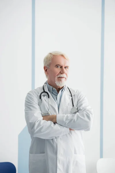 Starszy Lekarz Skrzyżowanymi Ramionami Patrzący Kamerę Szpitalu — Zdjęcie stockowe