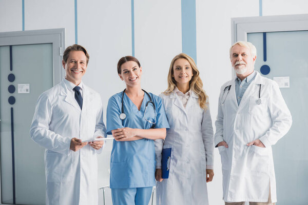 Doctors and nurse with clipboard and digital tablet looking at camera in clinic 