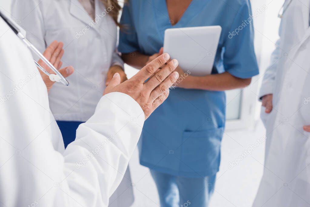 Cropped view of doctor standing near colleagues and nurse with digital tablet 