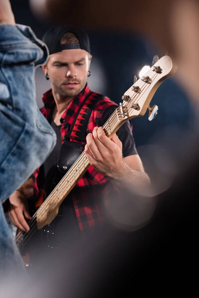 KYIV, UKRAINE - AUGUST 25, 2020: Rock band musician playing electric guitar on blurred foreground