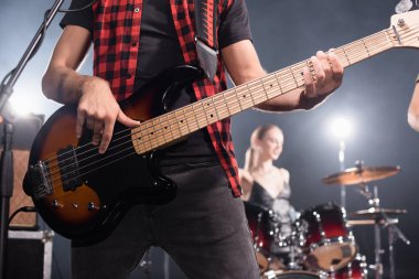 KYIV, UKRAINE - AUGUST 25, 2020: Rock band musician playing electric guitar with blurred drummer on background clipart