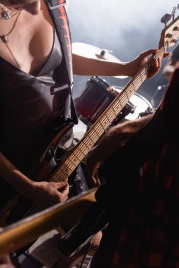 KYIV, UKRAINE - 25 Ağustos 2020: Ön planda bulanık gitaristle davulun yanında duran gitar tellerine dokunan kadın