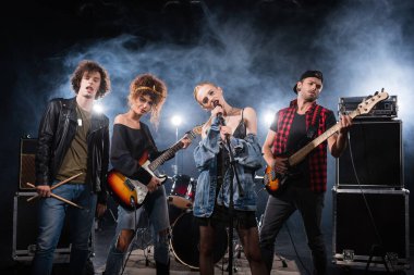 KYIV, UKRAINE - 25 AĞUSTOS 2020: Bas gitarlı müzisyenlerin yanında şarkı söyleyen rock grubunun vokalisti