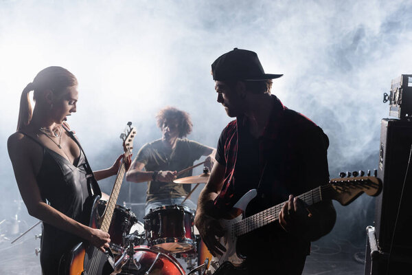 KYIV, UKRAINE - AUGUST 25, 2020: Rock band play electric guitars and drum kit with smoke on background