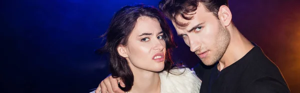 Man Hugging Irritated Brunette Woman Looking Camera Backlit Black Banner — Stock Photo, Image