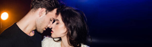 Страстный мужчина в черной рубашке стоит рядом с соблазнительной женщиной с закрытыми глазами, глядя на губы с подсветкой на черном, баннер