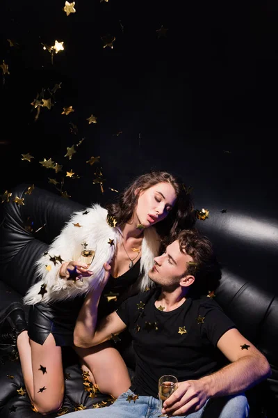 Passionate Boyfriend Holding Woman Jacket Sitting Sofa While Confetti Falling — Stock Photo, Image