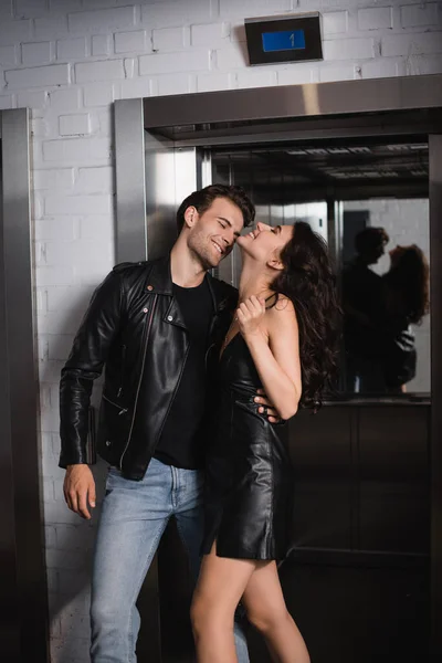 Smiling Man Leather Jacket Embracing Looking Happy Girlfriend Elevator Entrance — Stock Photo, Image