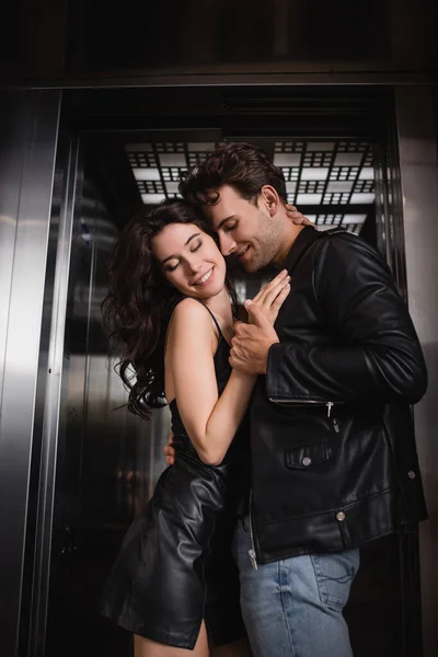 笑顔男抱擁と手を取ります官能的な女性の閉鎖目でエレベーターの入り口 — ストック写真