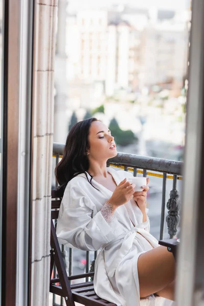 美しいブルネットの女性で白いローブバルコニーでコーヒーを飲む — ストック写真