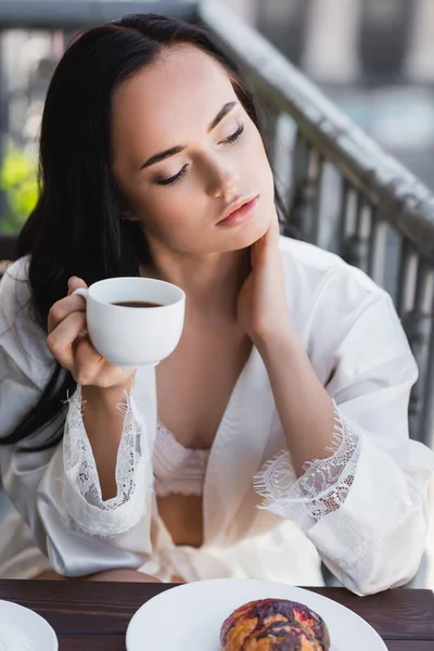 Brünette Frau Weißen Gewand Trinkt Kaffee Und Berührt Hals Auf — Stockfoto