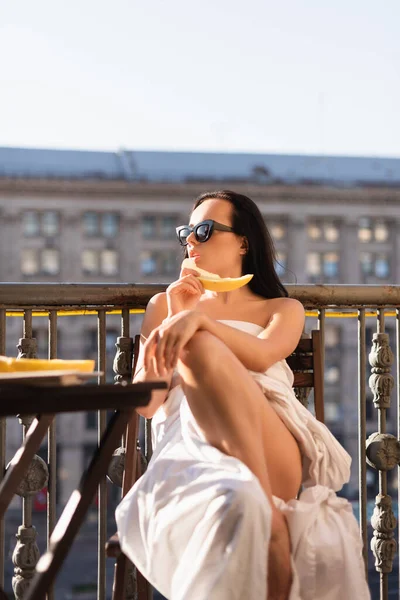 Sexy Brunette Woman Sunglasses Covered White Sheet Eating Melon Balcony — Stock Photo, Image