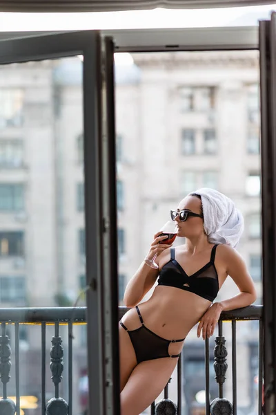 穿着黑色内裤头戴毛巾的性感女人在阳台上喝红酒 — 图库照片