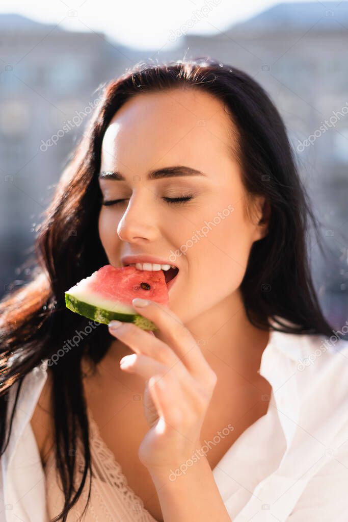 portrait of brunette woman eating watermelon with closed eyes