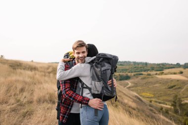 Sırt çantalı gülümseyen gezgin yolculuk boyunca Afrikalı Amerikalı kadınları kucaklıyor. 