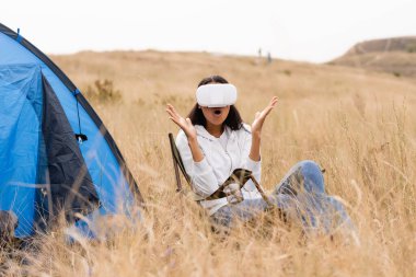 Heyecanlı Afrikalı Amerikalı kadın otlağın yanındaki çadırda VR kulaklık kullanıyor. 