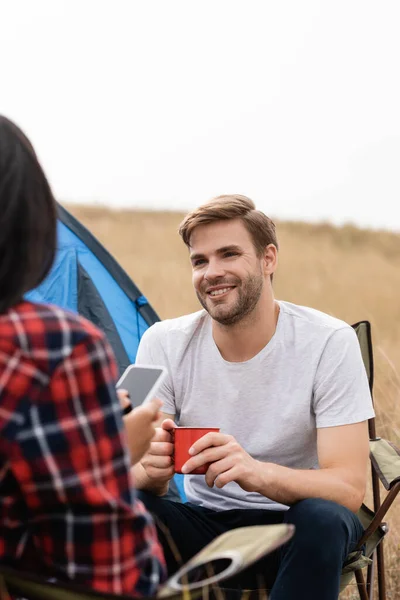 Smiling Man Holding Cup African American Girlfriend Smartphone Blurred Foreground — Stock Photo, Image