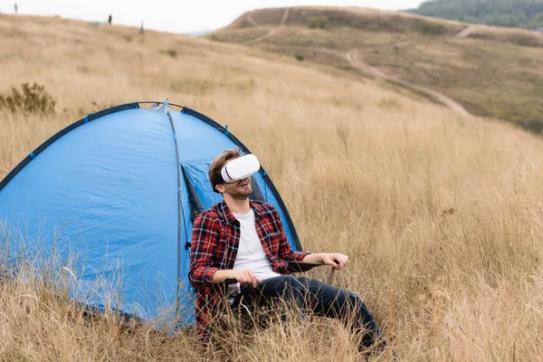 Smiling Man Using Headset While Sitting Tent Lawn — Stock Photo, Image