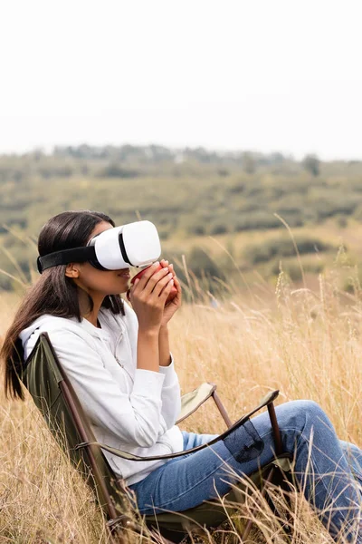 African American Woman Holding Cup While Using Headset Chair Grassy — Stock Photo, Image