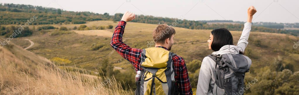 Smiling african american hiker showing yeah gesture near boyfriend outdoors, banner 