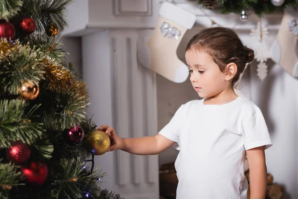 暖炉の近くに立ち クリスマスボールに触れる女の子家で松 — ストック写真