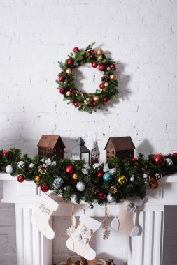 Noel çelengi şöminenin üstünde Noel baloları ve çoraplarla süslenmiş.