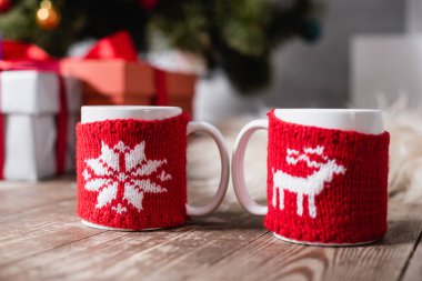 Tahta masada örgü Noel tutacağı olan bardakların seçici odağı