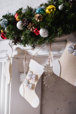 Noel çorapları, çam dalları ve Noel toplarıyla süslenmiş şömine.