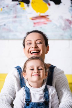Anne ve kızının arka planda resimle kameraya baktığı seçmeli odak.